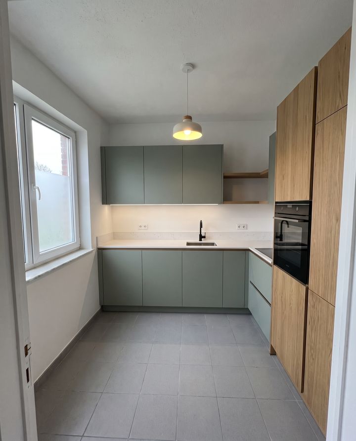 Dezelfde ruimte met een nieuwe keuken in salie groen en eik